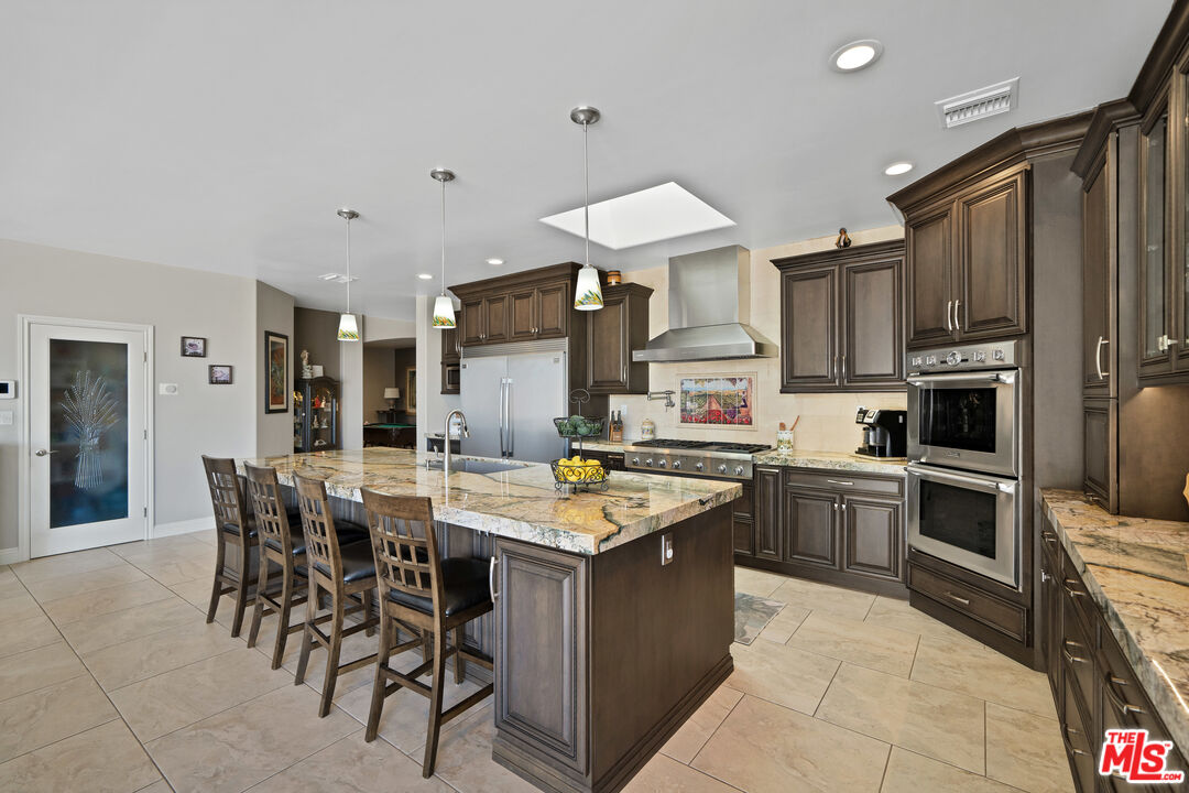 5437 Middlecrest Road Rancho Palos Verdes, CA 90275 - Photo 5 of 32 a kitchen with stainless steel appliances granite countertop a stove top oven a sink dishwasher a dining table and chairs with wooden floor