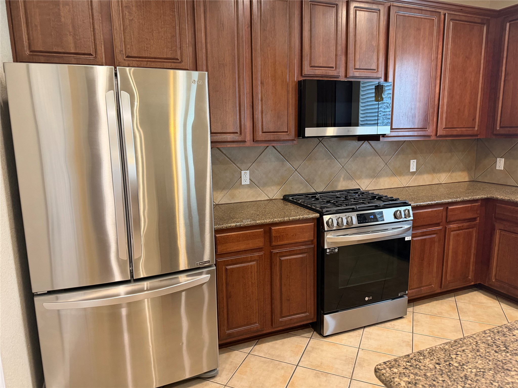 3021 Grand Mission Way Pflugerville, TX 78660 - Photo 13 of 31 A contemporary kitchen features rich cabinetry, stone counters, and modern stainless steel appliances.