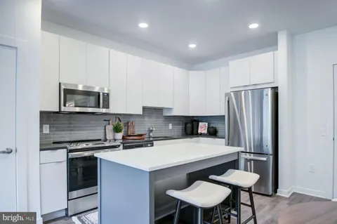 a kitchen with a sink a stove a refrigerator and white cabinets