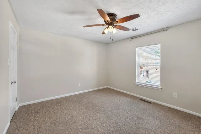 an empty room with windows and fan