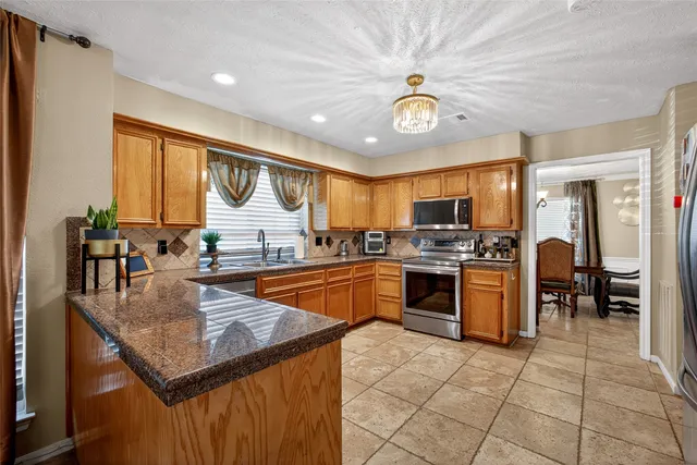 a kitchen with stainless steel appliances granite countertop a sink a stove counter space and cabinets