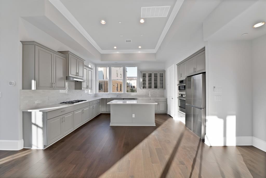 5437 Patterson Street Irving, TX 75039 - Photo 13 of 40 Kitchen with a center island, stainless steel appliances, gray cabinetry, dark wood-type flooring, and a tray ceiling