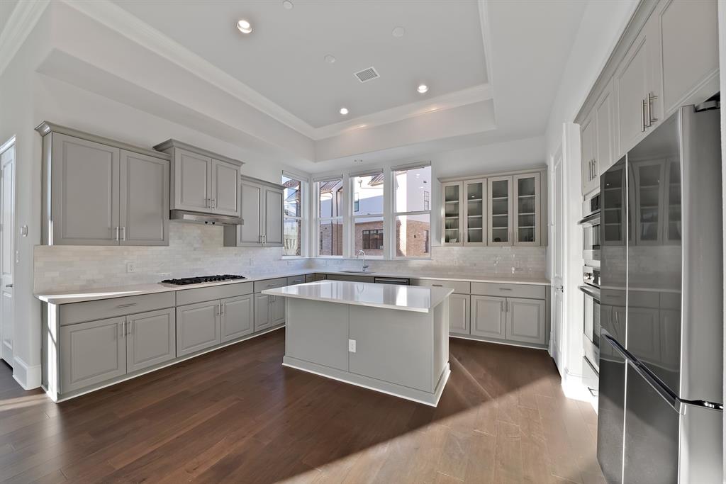 5437 Patterson Street Irving, TX 75039 - Photo 2 of 40 Kitchen with freestanding refrigerator, glass insert cabinets, a kitchen island, dark wood-type flooring, and tasteful backsplash