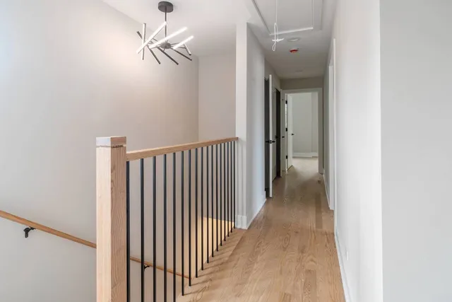 a view of a hallway with wooden floor and a chandelier