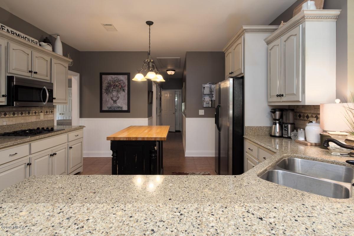 800 Pine Grove Church Road Culloden, GA 31016 - Photo 10 of 30 a kitchen with stainless steel appliances kitchen island granite countertop a refrigerator a stove a sink a microwave a dining table and chairs with wooden floor