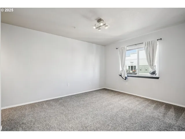an empty room with windows and chandelier fan