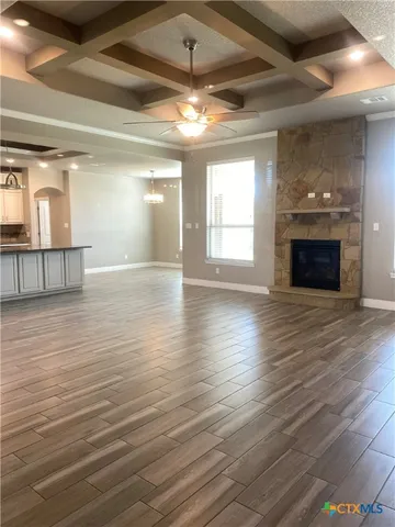 an empty room with wooden floor fireplace and windows
