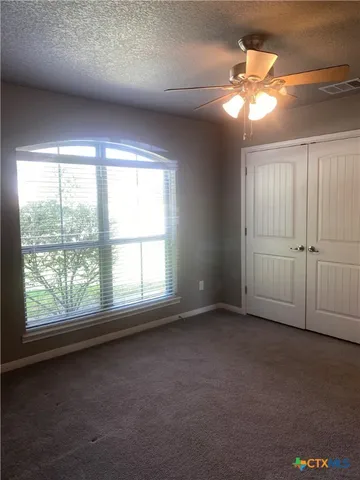 an empty room with a chandelier fan and windows