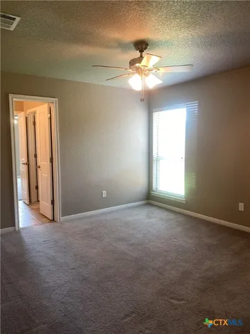 an empty room with windows and chandelier fan