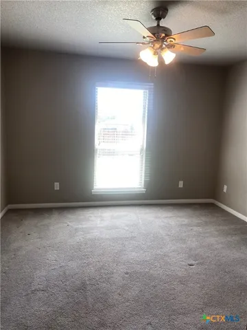 an empty room with windows and fan