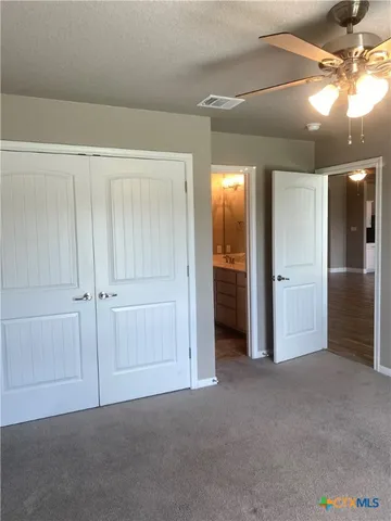 an empty room with closet and a chandelier fan