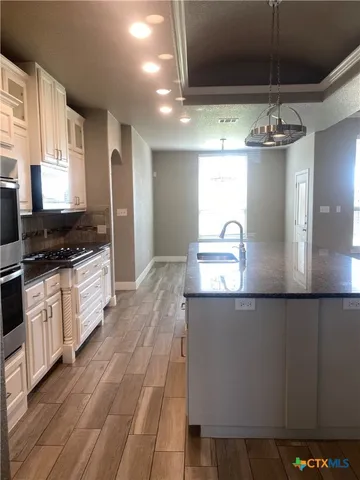 a kitchen with granite countertop a sink cabinets and wooden floor