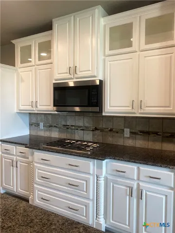 a kitchen with granite countertop white cabinets and window
