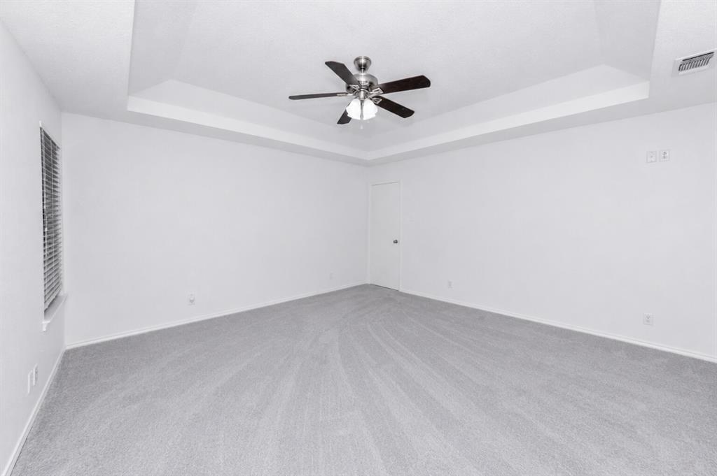 1001 Rosebud Drive Azle, TX 76020 - Photo 27 of 36 Spacious room featuring a tray ceiling with a ceiling fan, light gray carpeting, neutral wall paint, and a window with horizontal blinds