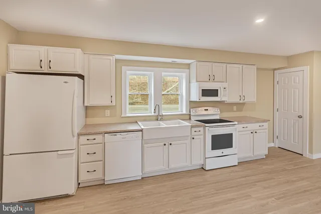 a kitchen with white cabinets and white appliances