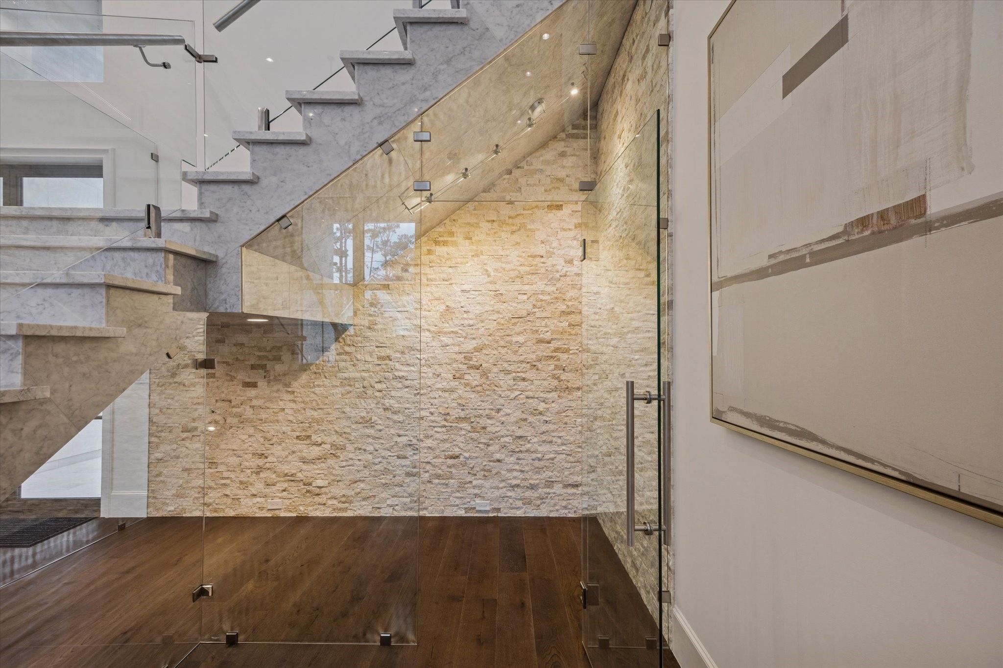318 Knipp Road Houston, TX 77024 - Photo 5 of 32 Fully glass-enclosed wine room nestled beneath the floating marble staircase, creating a stunning architectural focal point while offering a sophisticated wine storage and display.