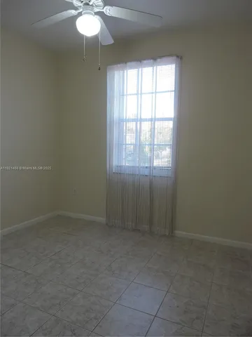 an empty room with chandelier fan and windows