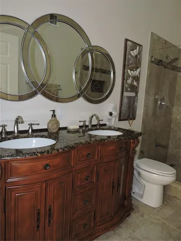 a bathroom with a granite countertop toilet sink and a mirror