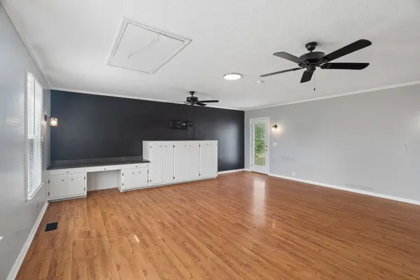 a view of empty room with wooden floor and fan