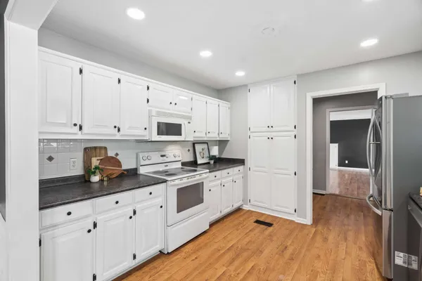 a kitchen with granite countertop white cabinets and white appliances