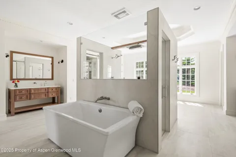a bathroom with a tub a sink and mirror