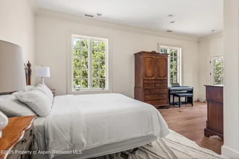 a bedroom with a bed and dresser with wooden floor