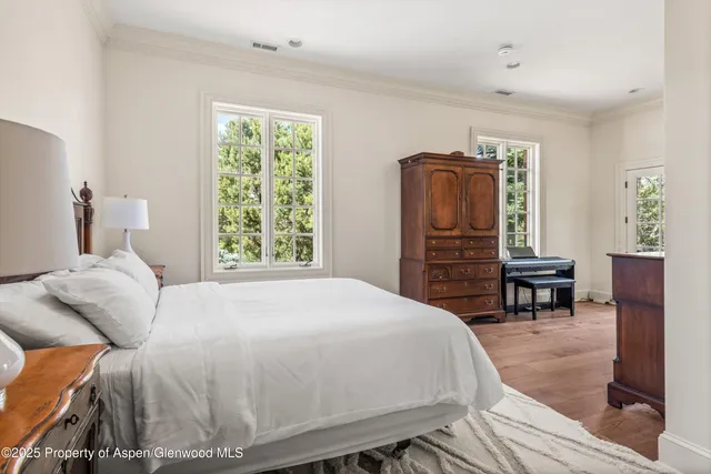 a bedroom with a bed and dresser with wooden floor