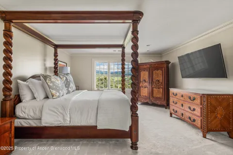 a bedroom with a bed and a flat tv screen on dresser