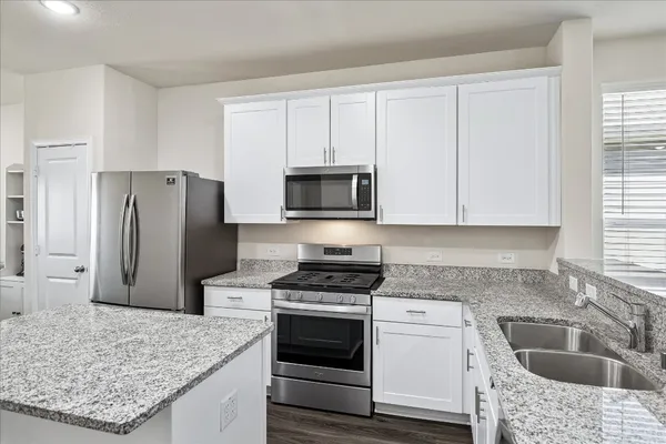 a kitchen with granite countertop a sink stove and refrigerator