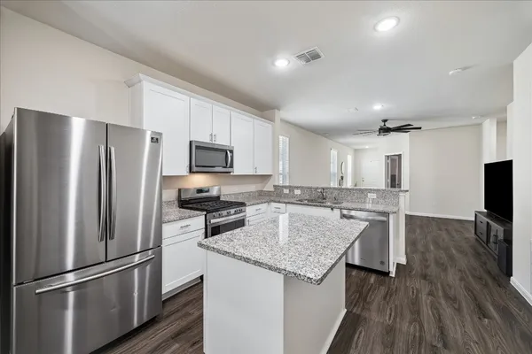 a kitchen with kitchen island a counter top space cabinets stainless steel appliances and wooden floor