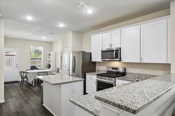a kitchen with stainless steel appliances granite countertop a stove top oven a sink a counter space and cabinets