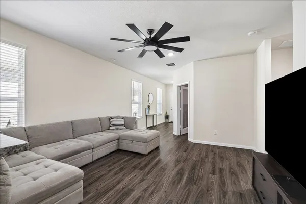 a living room with furniture a ceiling fan and a flat screen tv