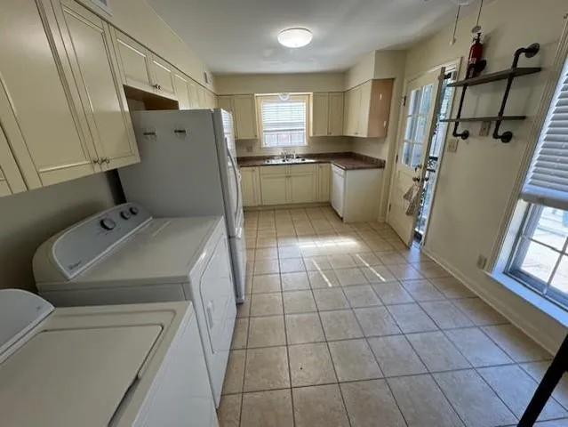 a view of a refrigerator in kitchen and an empty room in wooden floor
