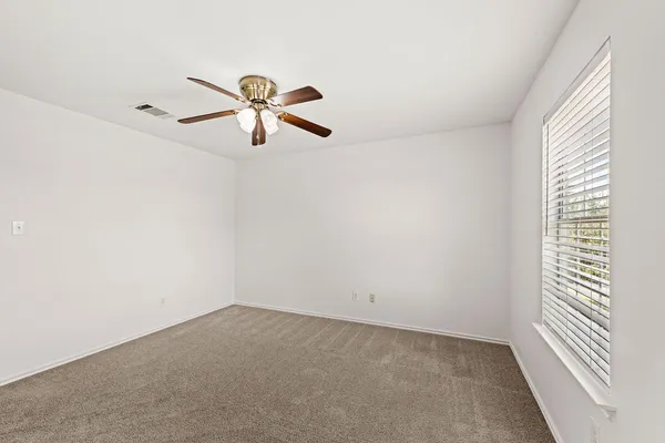 a view of a room with a ceiling fan and window