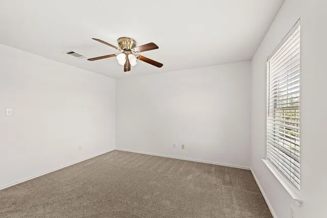 a view of a room with a ceiling fan and window
