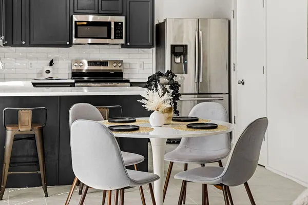 a kitchen with stainless steel appliances granite countertop a stove top oven a sink a dining table and chairs