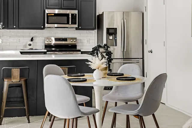 a kitchen with stainless steel appliances granite countertop a stove top oven a sink a dining table and chairs