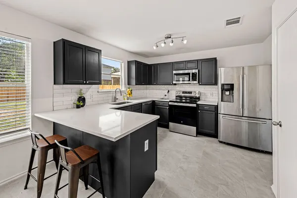 a kitchen with a refrigerator a microwave a sink and cabinets