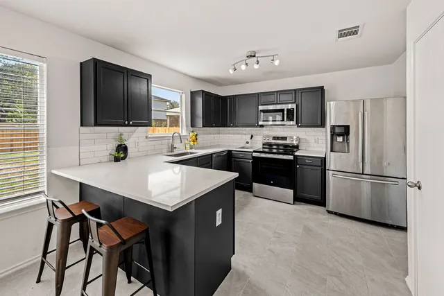 a kitchen with a refrigerator a microwave a sink and cabinets