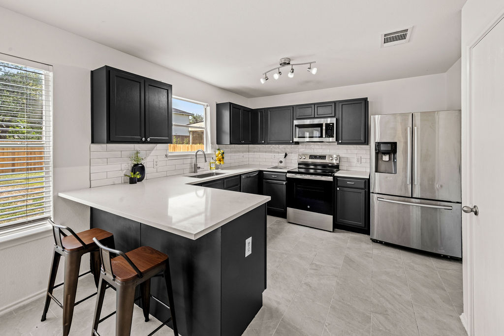 525 Meadow Park Drive Georgetown, TX 78626 - Photo 5 of 39 a kitchen with a refrigerator a microwave a sink and cabinets