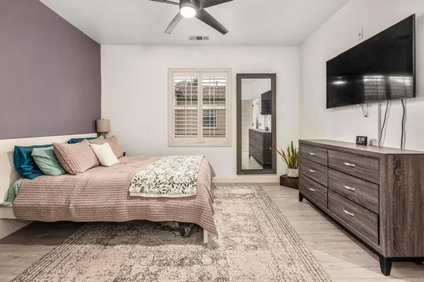 a bedroom with a bed television on desk and a flat screen tv