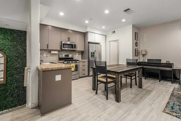 a kitchen with kitchen island granite countertop a sink a counter top space and stainless steel appliances