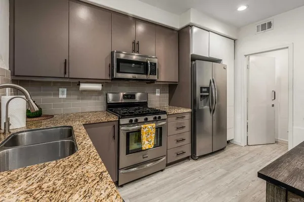 a kitchen with stainless steel appliances granite countertop a refrigerator a stove a sink and a microwave