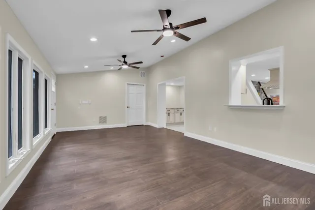 an empty room with wooden floor and ceiling fan