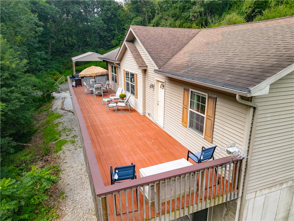 7353 Farrier Road Orefield, PA 18069 - Photo 2 of 74 An expansive wooden deck spans the side of this home, bordered by lush woodland scenery.