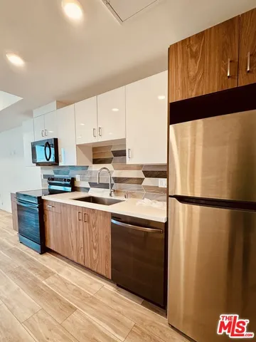 a kitchen with stainless steel appliances a refrigerator sink and white cabinets
