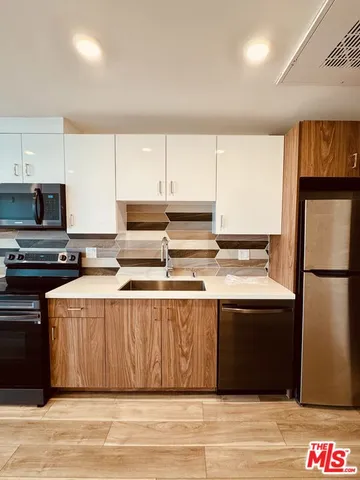 a kitchen with stainless steel appliances granite countertop a refrigerator a stove a sink and a microwave