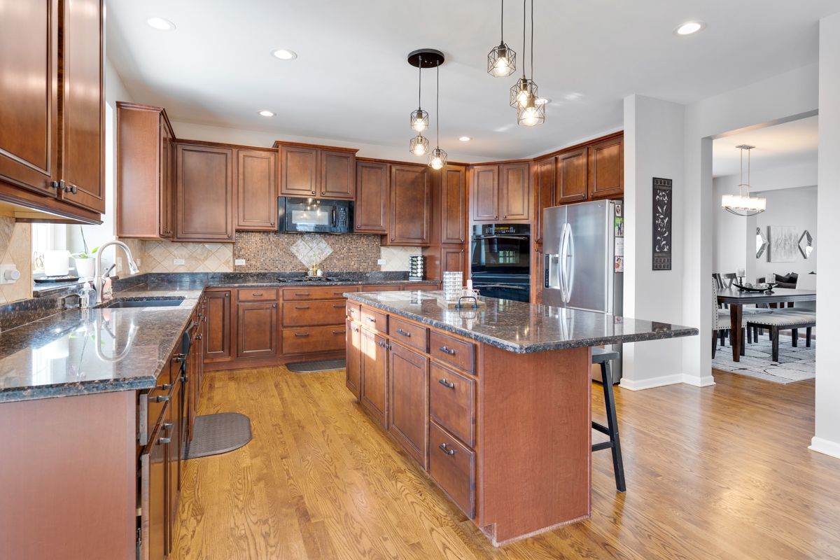 3001 Wagon Road Elgin, IL 60124 - Photo 11 of 39 a large kitchen with stainless steel appliances kitchen island granite countertop a large kitchen island a stove a refrigerator a sink a dining table and chairs with wooden floor