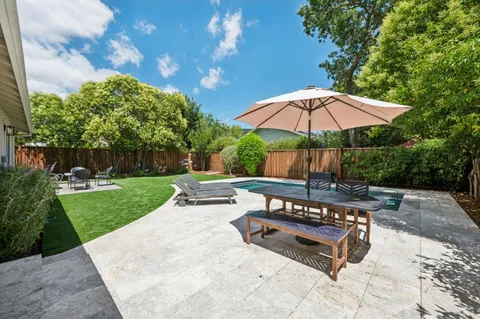 a view of a backyard with table and chairs potted plants and a large tree