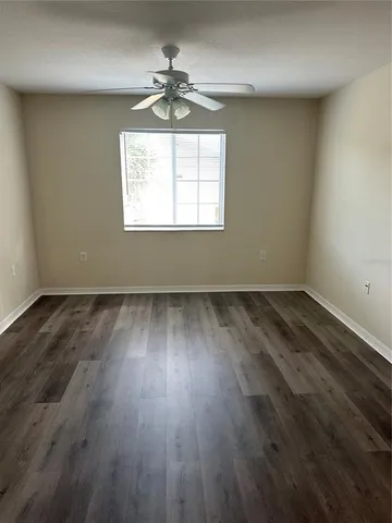 an empty room with wooden floor chandelier and windows